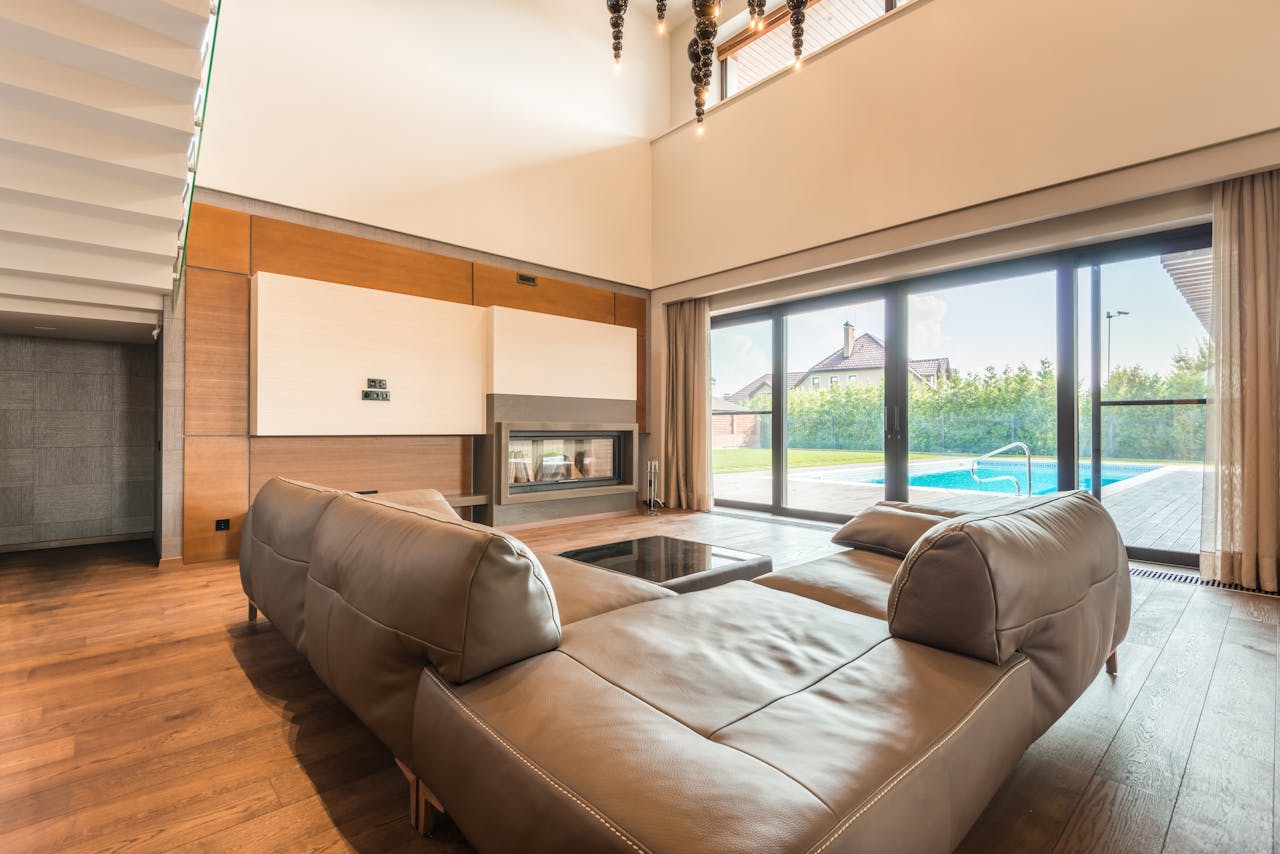 about-img Spacious modern living room featuring a leather sofa and glass doors overlooking a swimming pool.